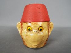 A vintage Manor Ware money bank in the form of a monkey wearing a fez, approximately 8 cm (h).