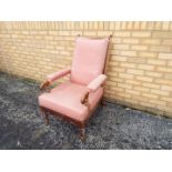 A wooden armchair with upholstered seat, back and armrests, on castors.