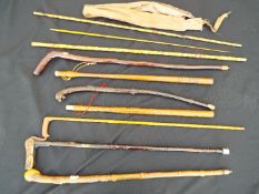 A collection of walking sticks and a vintage part fishing rod of bamboo construction and similar.