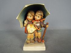 Hummel - A large Hummel figural group depicting two children standing under an umbrella,