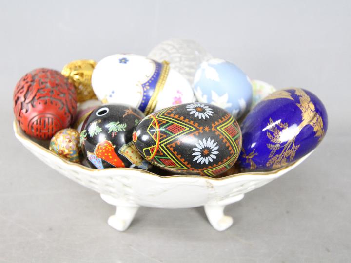 A bowl containing a collection of egg ornaments to include stone, glass, champlevé,