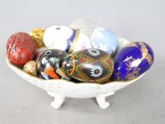 A bowl containing a collection of egg ornaments to include stone, glass, champlevé,