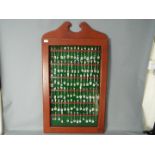 A display case housing a quantity of predominantly plated souvenir collector spoons,