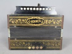 A Hohner ten button accordion in gilt decorated ebonised case, made in Germany,