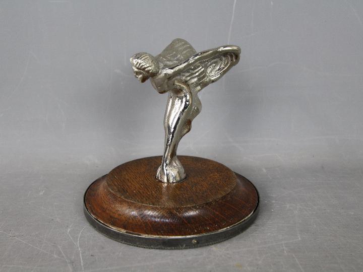 A Flying Lady car mascot on wooden base,