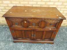 A television cabinet with fall front upper section over twin doors,
