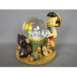 A Disney musical snow globe entitled 'Toyland' featuring Pinocchio, approximately 20.5 cm (h).