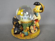 A Disney musical snow globe entitled 'Toyland' featuring Pinocchio, approximately 20.5 cm (h).