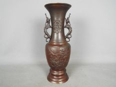 A large bronze vase with relief decoration of birds and flowers, twin dragon handles to the neck,