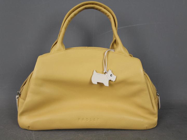 A lady's mustard coloured handbag marked Radley