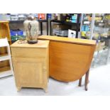 A drop leaf table, cupboard and lamp.