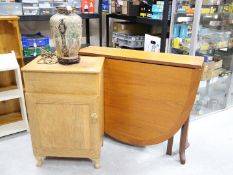 A drop leaf table, cupboard and lamp.