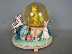 A Disney musical snow globe featuring Winnie The Pooh characters, approximately 18 cm (h).