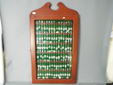 A display case housing a quantity of predominantly silver souvenir collector spoons with a small