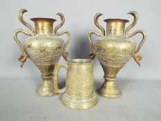 A pair of Indian twin handled vases with intricate, chased decoration,