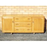 An Ercol sideboard having a central section of three drawers flanked by cupboards,