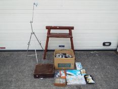 An artist's easel and a large quantity of paints and accessories.