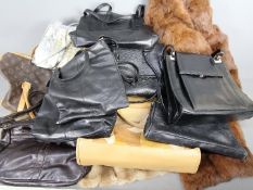 A collection of handbags and two fur coats.
