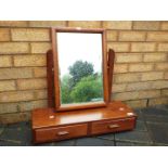 A table top swing mirror over two drawers.