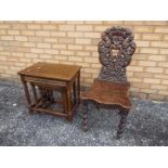 A nest of three tables and a highly carved hall chair.