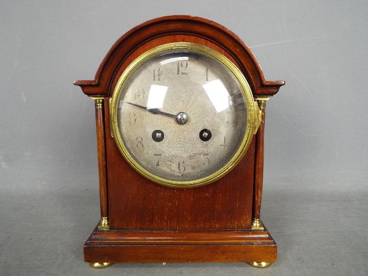A French arch top mantel clock, Arabic numerals to a white metal, engine turned dial, with key,