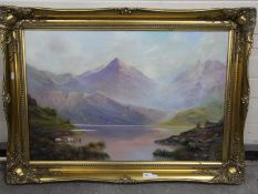 A gilt framed oil on canvas landscape scene depicting cattle taking water at a loch with a