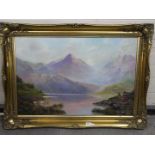 A gilt framed oil on canvas landscape scene depicting cattle taking water at a loch with a