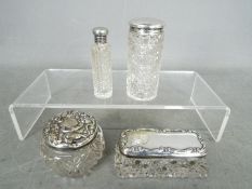 Four silver topped dressing table jars / containers, various assay and date marks.