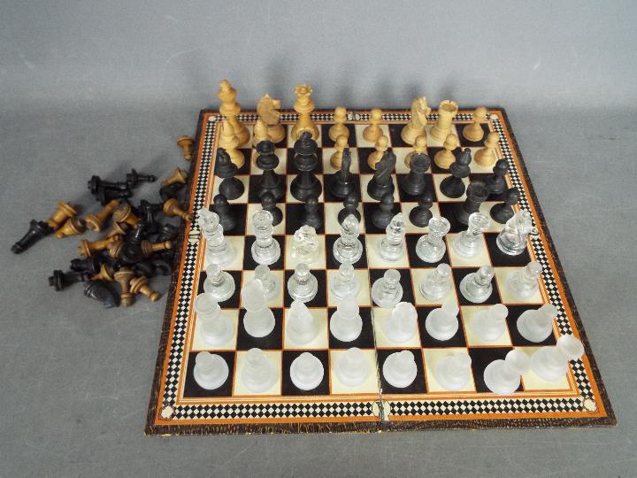 Three chess sets to include a glass set with 7.5 cm king and two wooden set, the larger with 8.