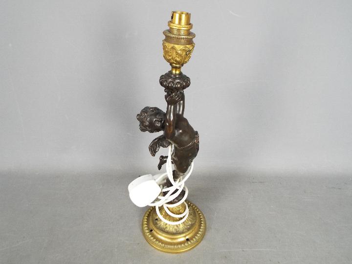 A decorative table lamp in the form of a standing putto, approximately 42 cm (h) including fitting.