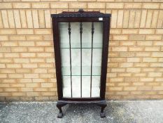 A single door display cabinet with two glass shelves, raised on four ball and claw supports,