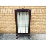 A single door display cabinet with two glass shelves, raised on four ball and claw supports,