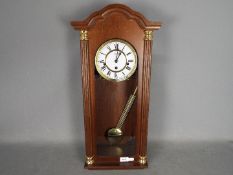 A modern Hermle Vienna style wall clock with key and pendulum.