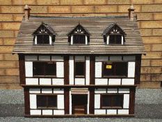 An illuminated hand built wooden three storey Tudor style dolls house,