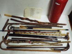 A collection of walking sticks in a stick stand including two with white metal / silver mounts,