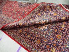 A large red ground Persian Kashan carpet measuring approximately 290 cm x 400 cm All items must be