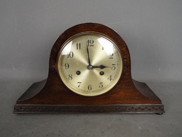 An oak cased Napoleons hat mantel clock with Arabic numerals to the dial, with key and pendulum.