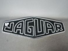 A white metal sign marked Jaguar,