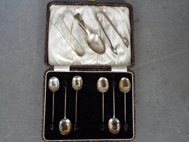 A George V cased set of six silver coffee spoons (tongs lacking) with bean terminals,