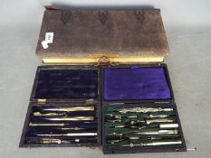 A leather bound photograph album and two cased sets of technical drawing instruments.