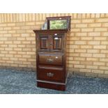 A mahogany commode with carved detail, brass drop handles, mirror top,