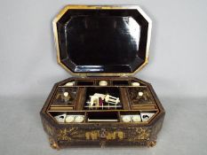 An Oriental lacquered box with fitted interior raised on four gilt supports,