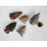 Five knapped arrow heads and a piece of tiger's eye quartz.