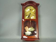 A modern, mahogany cased, AMS wall clock with key and pendulum.