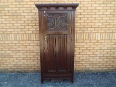 A Waring & Gillows single door wardrobe with carved decoration of fruiting vine,