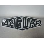 A white metal sign marked Jaguar, approx