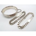 A silver hinged bangle having chased scrolling decoration to one half,