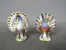 A matched pair of hand painted porcelain figures depicting Peacocks, likely Meissen,