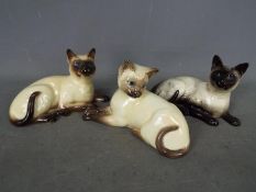 Beswick - Three Beswick cat figurines, all recumbent Siamese, largest approximately 12 cm (h).