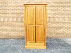 A pine single door wardrobe with lower drawer, approximately 183 cm x 89 cm x 52 cm.